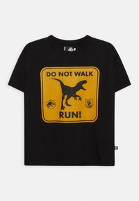 Černé bavlněné tričko s žlutou grafikou, na které je silueta dinosaura a nápis "NECHODIT, BĚŽTE!" tučným písmem.