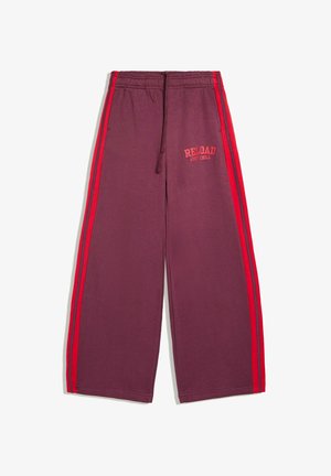 Pantalon bordeaux à jambes larges avec bandes latérales rouges, taille élastique, cordon, poches et texte "RELOAD JUST CHILL" sur le côté avant droit.