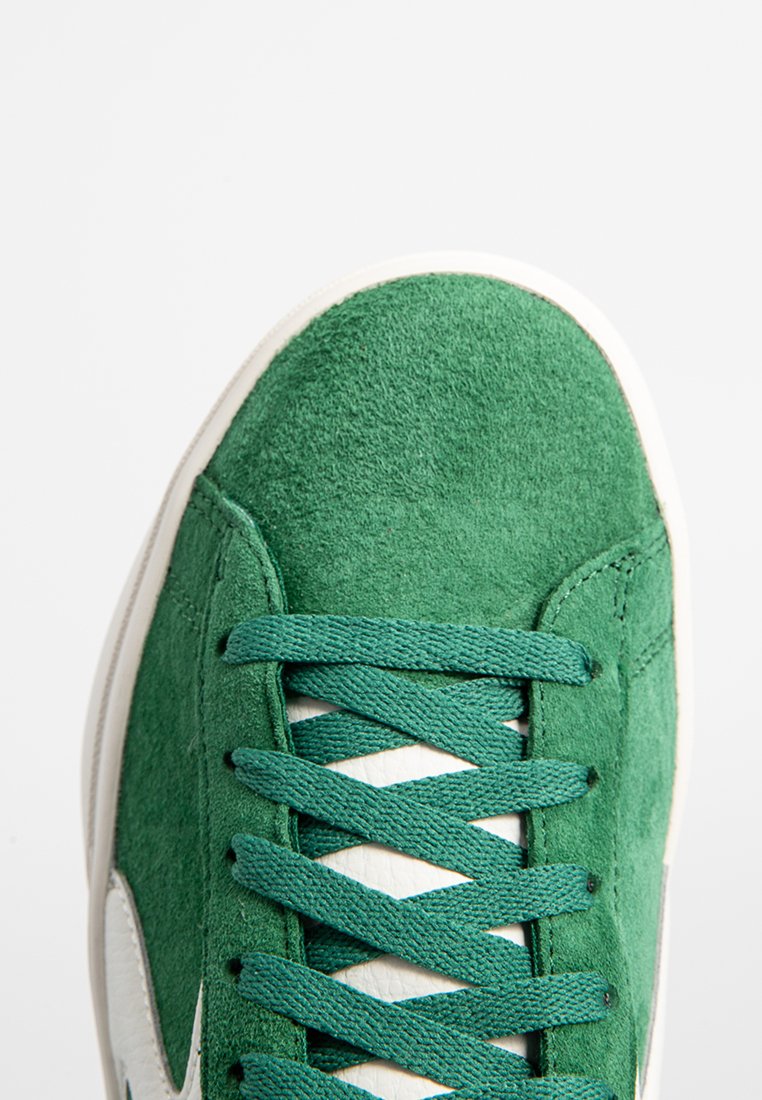 Groene suède sneaker met een gestructureerde afwerking, voorzien van groene veters, een witte rubberen zool en een contrasterend wit zijlogo.