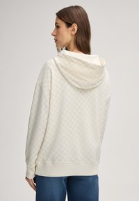 Hoodie de couleur crème avec une texture à motif, doté d'une grande capuche, d'une coupe décontractée et de poignets et d'un ourlet côtelés.