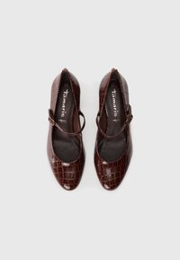 Pair of dark brown, crocodile-patterned Mary Jane flats with rounded toes and buckle straps on white background.