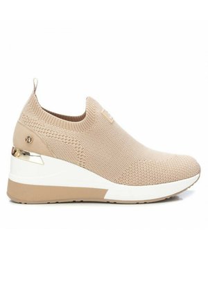 Zapatilla beige sin cordones con parte superior de punto, suela de cuña elevada y acento metálico en el talón. Superficie texturizada y banda elástica para un mejor ajuste.