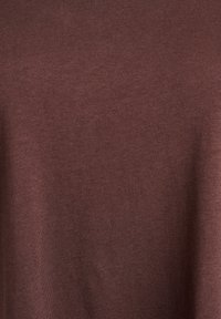 Braunes Baumwoll-T-Shirt mit glatter Textur. Der Stoff weist eine einheitliche, einfarbige Farbe ohne Muster oder sichtbare Applikationen auf.