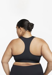 Sort sports-BH med racerback-design, glatt tekstur og bredt bånd, satt sammen med svarte leggings, sett bakfra.