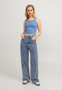 Top de alças azul com textura canelada combinado com calças de ganga azul de cintura alta e corte largo. As calças incluem bolsos e fecho com botão.