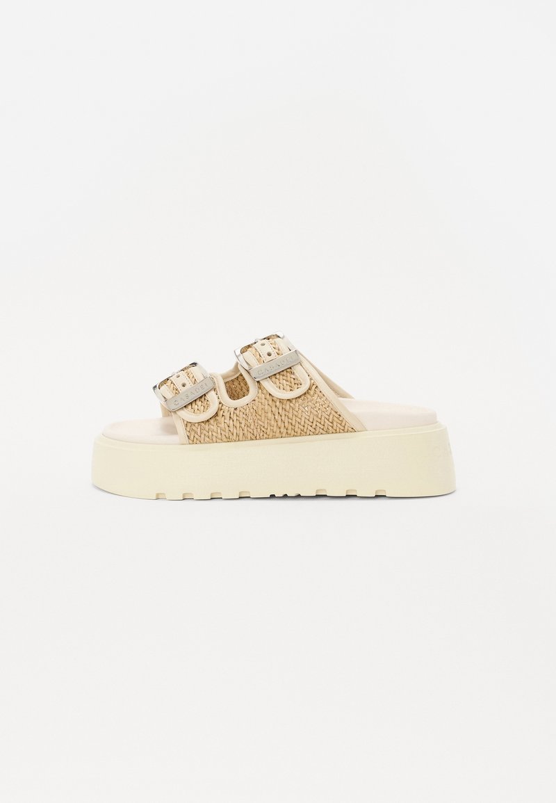 Sandales compensées beige en tissu tressé avec deux boucles ajustables, semelle épaisse blanche, dessus texturé et semelle plate conçue pour le confort.