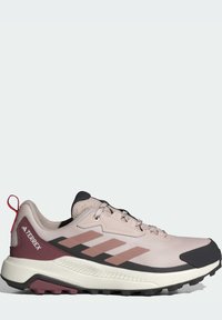 Light pink athletic shoe with black and maroon accents, textured mesh upper, protective toe cap, and rugged outsole for traction.