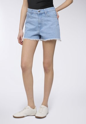 Shorts in denim azzurro chiaro con orlo sfrangiato, caratterizzati da vita alta e tasche frontali, abbinati a sneakers bianche.