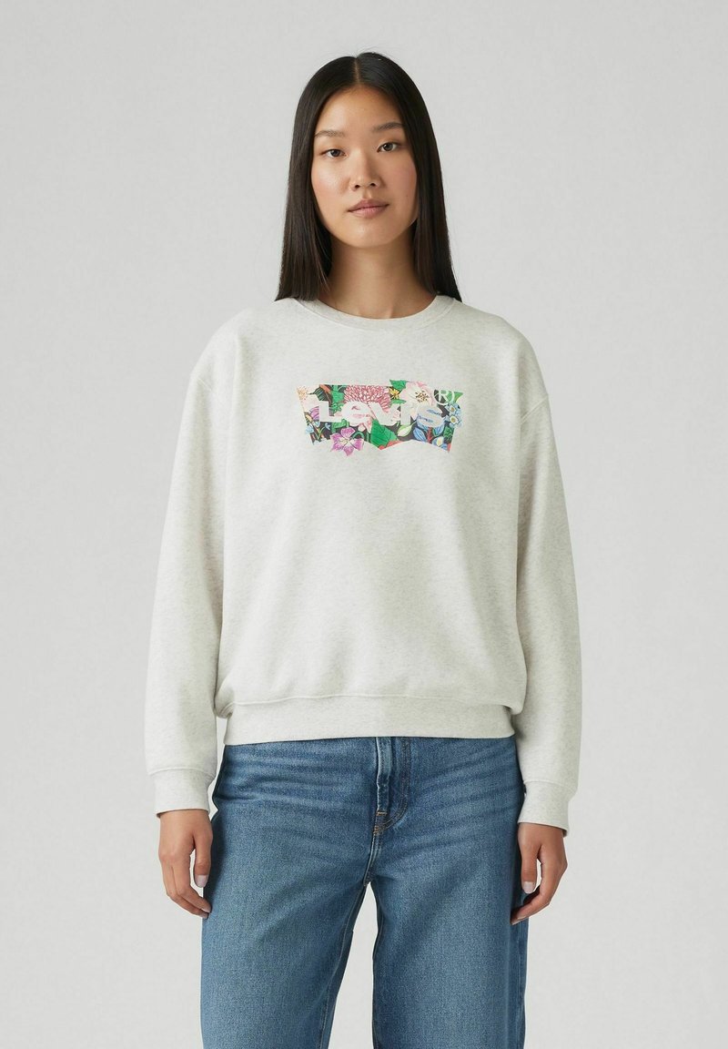 Sweatshirt gris à col rond, avec un graphique floral coloré sur le devant. Texture douce et poignets côtelés aux manches et à la taille.