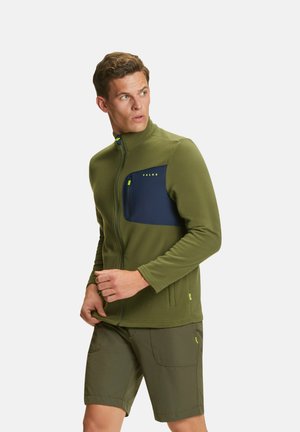 Veste en polaire verte avec une poche avant bleue marine, fermeture éclair et col montant ; associée à un short olive, les deux présentant des accents jaunes vifs.