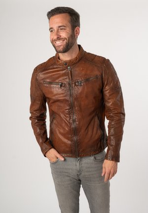 Bruine leren motorjack met een mandarin kraag, ritsopening aan de voorkant en zakken, en gestikte details op de schouders. Gladde textuur.