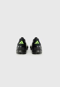 Baskets de sport noires avec une tige synthétique texturée, présentant une accentuation verte au niveau du talon et une semelle en caoutchouc durable.