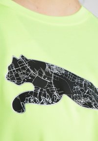 Silhuett av en svart panter med ett vitt gatunätmönster tryckt på en neongrön t-shirt.