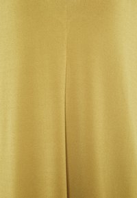 Złoto-żółta tkanina o gładkiej fakturze, z centralnym pionowym szwem biegnącym przez środek.