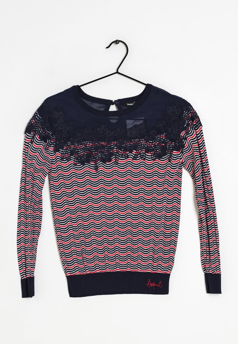 Granatowy sweter z falistym wzorem w czerwonym i białym kolorze. Posiada koronkowe wykończenie przy dekolcie oraz otwarcie w kształcie łezki z tyłu.
