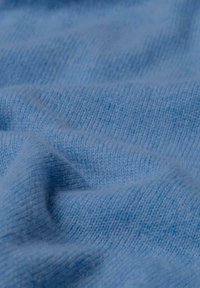 Hellblau gestrickter Stoff mit einer weichen Textur, der feine Rippen und subtile Farbvariationen im gesamten Material aufweist.