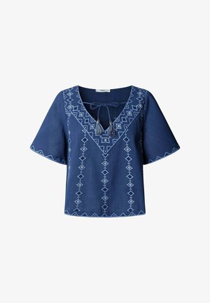 Blusa azul de manga corta con bordado geométrico blanco, escote en V atado con cordones con borlas y mangas acampanadas.