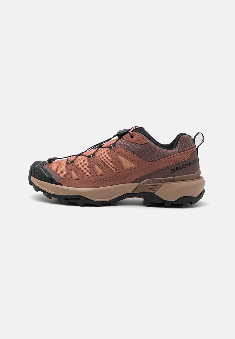 Salomon hiking shoe, featuring a brown mesh upper with black accents, a textured sole, and quick-lace system for secure fitting.