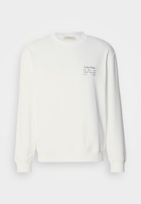 Sweat blanc à manches longues avec poignets côtelés et petit logo texte noir sur la poitrine gauche indiquant Calvin Klein et une adresse à New York.