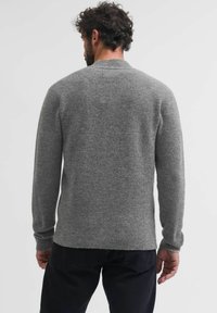 Suéter de lana gris con mangas largas, cuello redondo y puños acanalados. Presenta una textura suave y un corte relajado. Vista trasera de la prenda.