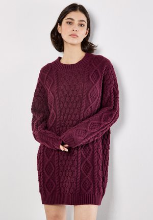Vestido de punto burdeos con patrones texturizados y mangas largas. Presenta un cuello redondo y puños y dobladillo acanalados. Corte relajado.