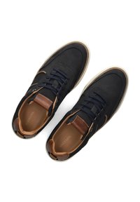 Donker marineblauwe sneakers met een gladde afwerking, bruine leren accenten, geperforeerde details en marineblauwe veters. Lichte zool met een gestructureerd patroon.