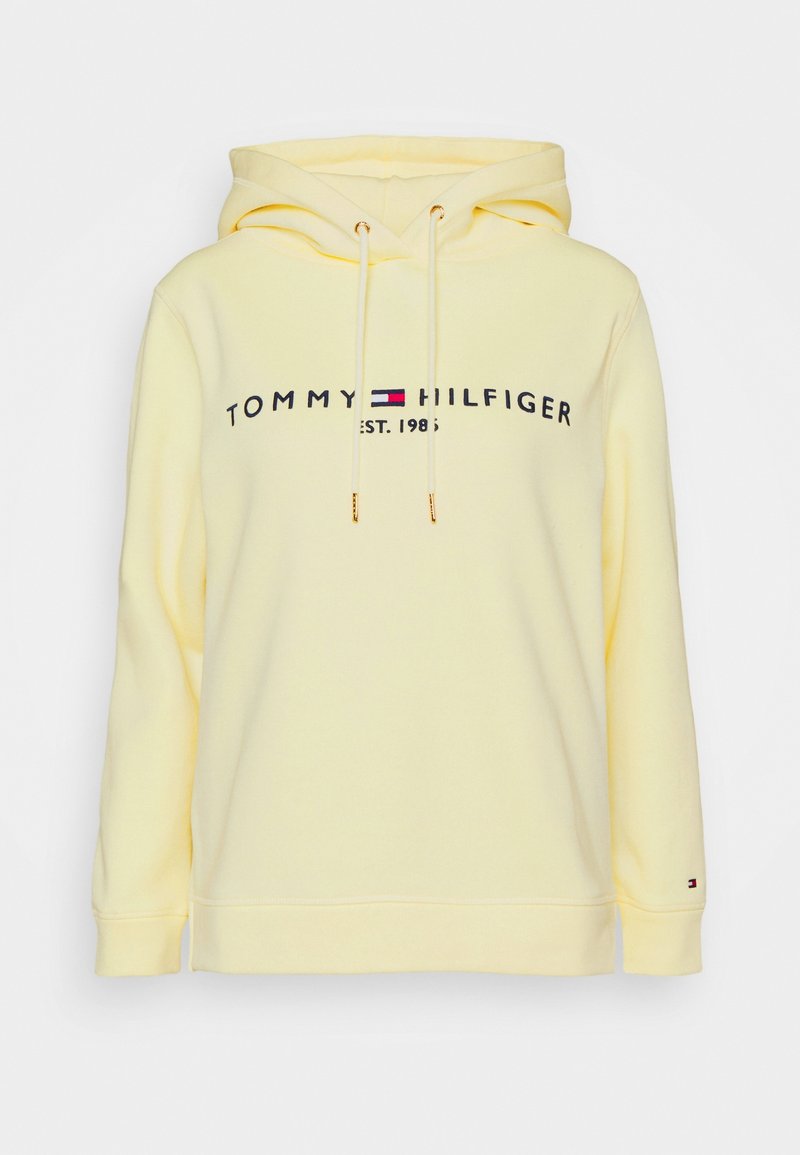 Sudadera de algodón amarilla con capucha ajustable, que presenta un logo frontal "TOMMY HILFIGER EST. 1985" en color marino y rojo. Puños y dobladillo de canalé.