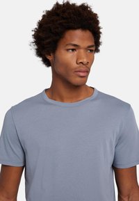 T-shirt azzurro chiaro a maniche corte realizzato in stoffa morbida. Presenta un collo rotondo e dettagli di cucitura minimi. Design semplice e classico senza motivi.