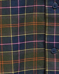 Gros plan sur un tissu foncé avec un motif à carreaux multicolores jaune, rose, orange et bleu, avec deux boutons bleu foncé sur le côté droit.