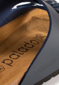 Marinblå sandal med en texturerad ovansida och en mjuk, tan mocka fotbädd. Sulan är mörk med subtil logotyp.