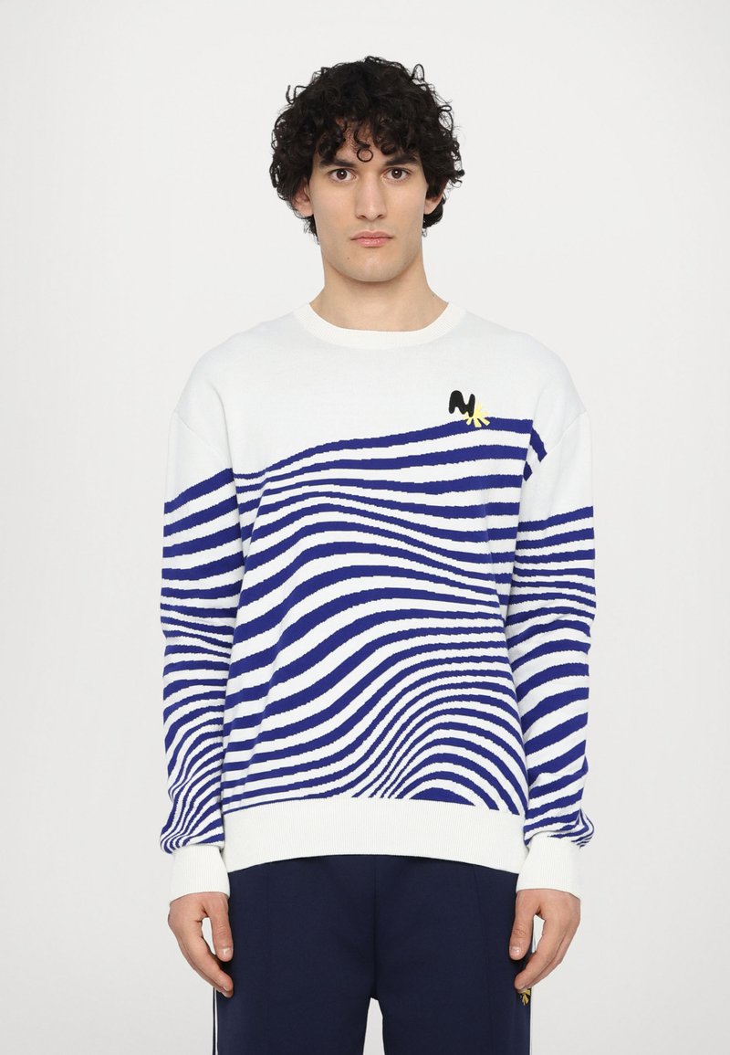 Weißer Strickpullover mit blauen, wellenförmigen Streifen, gerippten Bündchen und Saum sowie einem kleinen schwarz-gelben Logo auf der Brust.