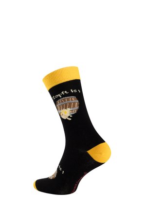 Schwarze Socke mit gelbem Bündchen, Zehen- und Fersenbereich, mit einem Holzfass- und Blumendesign sowie teilweise weißem Text darüber und darunter.