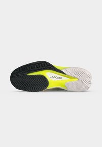 Σόλα αθλητικού παπουτσιού Lacoste με μαύρα, λευκά και νέον κίτρινα τμήματα και υφασμένα μοτίβα πρόσφυσης σε απλό φόντο.