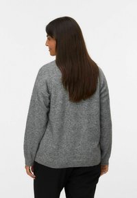 Suéter gris de punto con un corte holgado, que presenta un escote redondeado y mangas largas, hecho de un material suave similar a la lana.