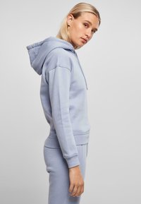Sudadera azul claro hecha de una tela suave, con capucha ajustable, puños acanalados y un corte relajado, combinada con pantalones de chándal a juego.