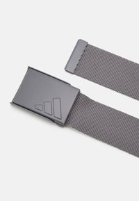 Grå vævet bælte med en rektangulær metalspænde, der har et trekantet design. Bæltet er fladt og struktureret, velegnet til afslappet brug.