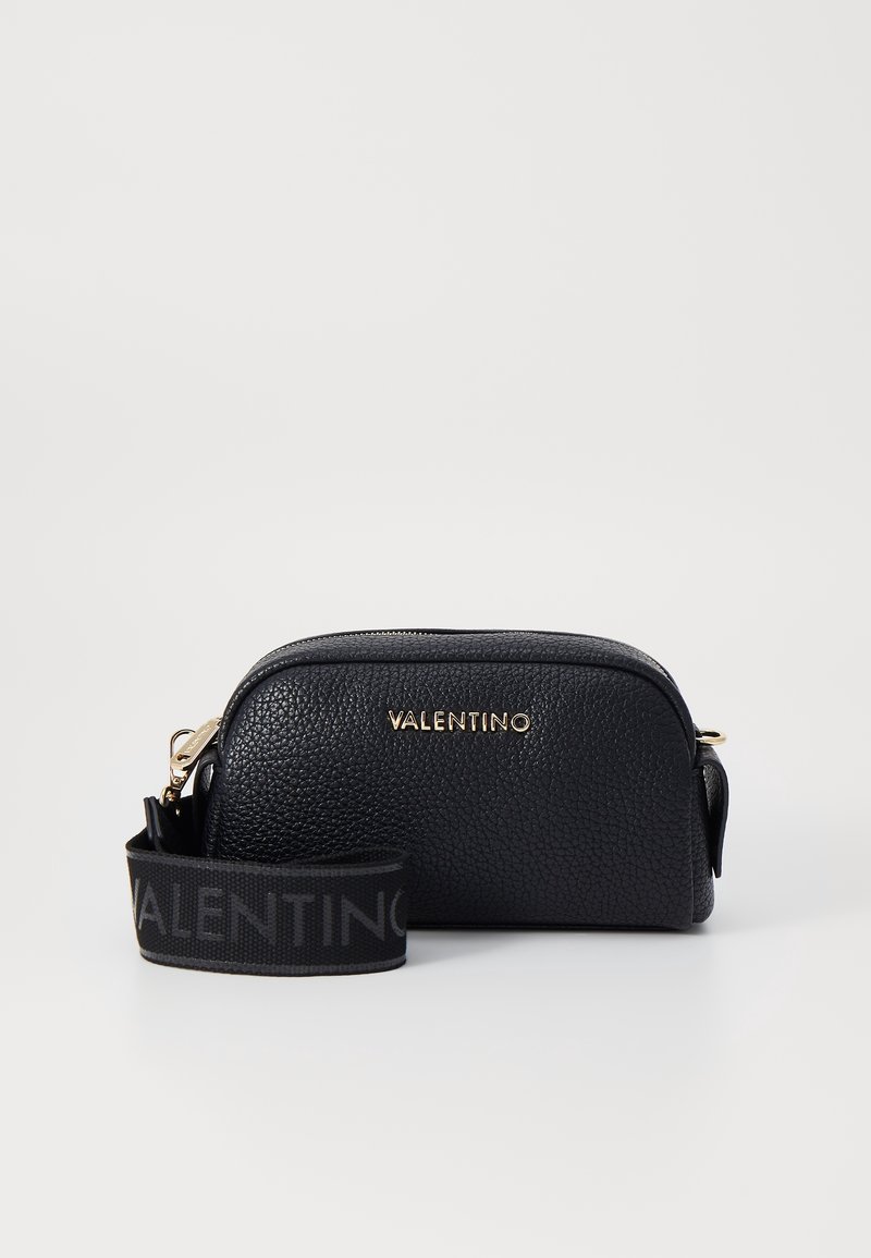 Black leather crossbody bag with a textured finish. Features gold-toned logo and a black strap with embossed lettering. Rounded shape.
