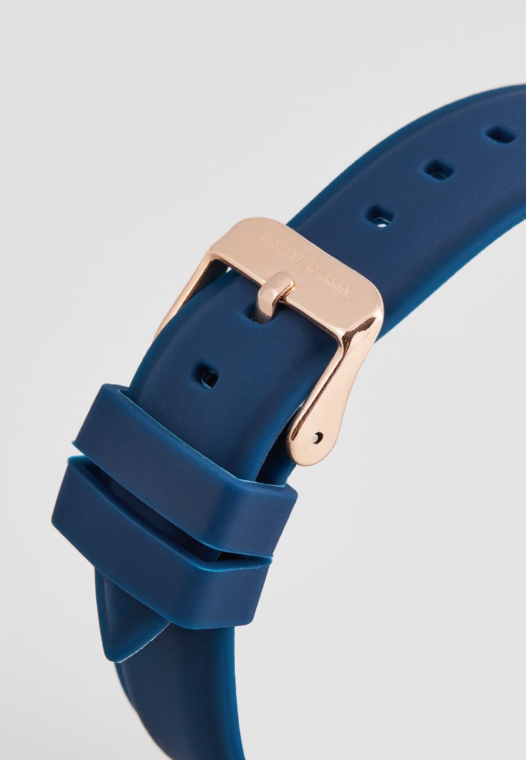 Bracelet de montre en silicone bleu avec une boucle en métal rose doré, affichant une texture lisse et des trous réglables pour personnalisation de la taille.