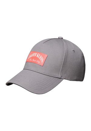 Grå Calvin Klein baseballkasket med buet skygge og rød rektangulær logo-patch med teksten "Calvin Klein New York City."