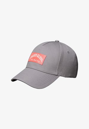 Grå Calvin Klein baseballkasket med buet skygge og rød rektangulær logo-patch med teksten "Calvin Klein New York City."