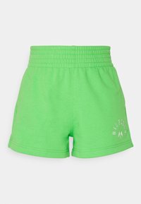 Pantalones cortos elásticos de cintura alta en color verde brillante con bolsillos laterales y pequeño logo impreso en blanco en la parte inferior de la pierna izquierda.