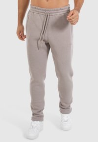 Lichtgrijze sweatpants met een elastieke tailleband en trekkoord. Heeft zijzakken en een tapered leg ontwerp. Gestyled met witte sneakers.