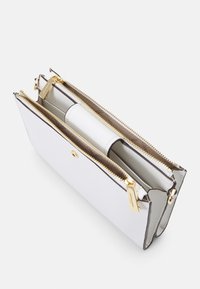 Portefeuille en cuir blanc avec deux compartiments zippés, matériel doré et doublure beige. Présente des lignes épurées et un design minimaliste.