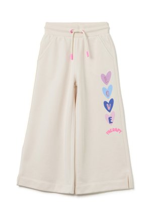 Pantaloni della tuta color crema con vestibilità comoda, dotati di una vita con coulisse, tasche laterali e grafiche a forma di cuore colorate su una gamba.