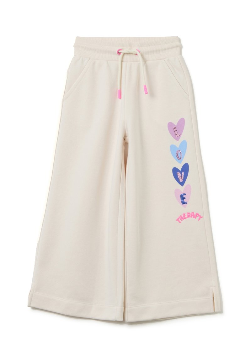 Crème kleurige sweatpants met een relaxte pasvorm, voorzien van een trekkoord in de taille, zijzakken en kleurrijke hartafbeeldingen op één been.