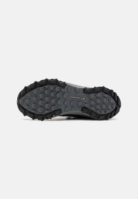 Semelle de chaussure de randonnée Columbia grise et noire avec motif hexagonal et crampons profonds pour une bonne adhérence sur fond blanc.