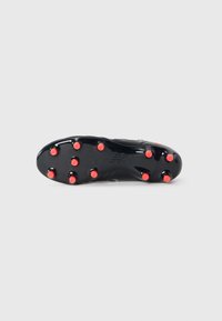 Crampon de soccer noir au design épuré, avec une texture lisse et des pointes rouges sur la semelle extérieure pour une meilleure traction. Logo de la marque visible.