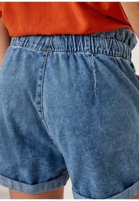 Denim shorts with an elastic waistband, light blue color, rolled cuffs, and a soft texture, featuring a subtle fade and stitching details.