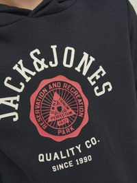 Sudadera navy con un gráfico redondo rojo que incluye el texto: "JACK & JONES," "PARQUE DE RESERVAS Y RECREACIÓN," y "QUALITY CO. DESDE 1990."
