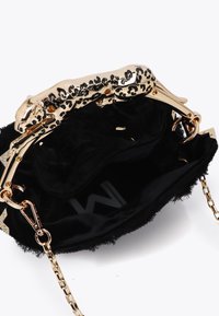 Čierna kožená kabelka so zlatým uzáverom s leopardím vzorom, s hladkým vnútrom a reťazovým popruhom. Výrazné detaily zahŕňajú strapce na okrajoch.